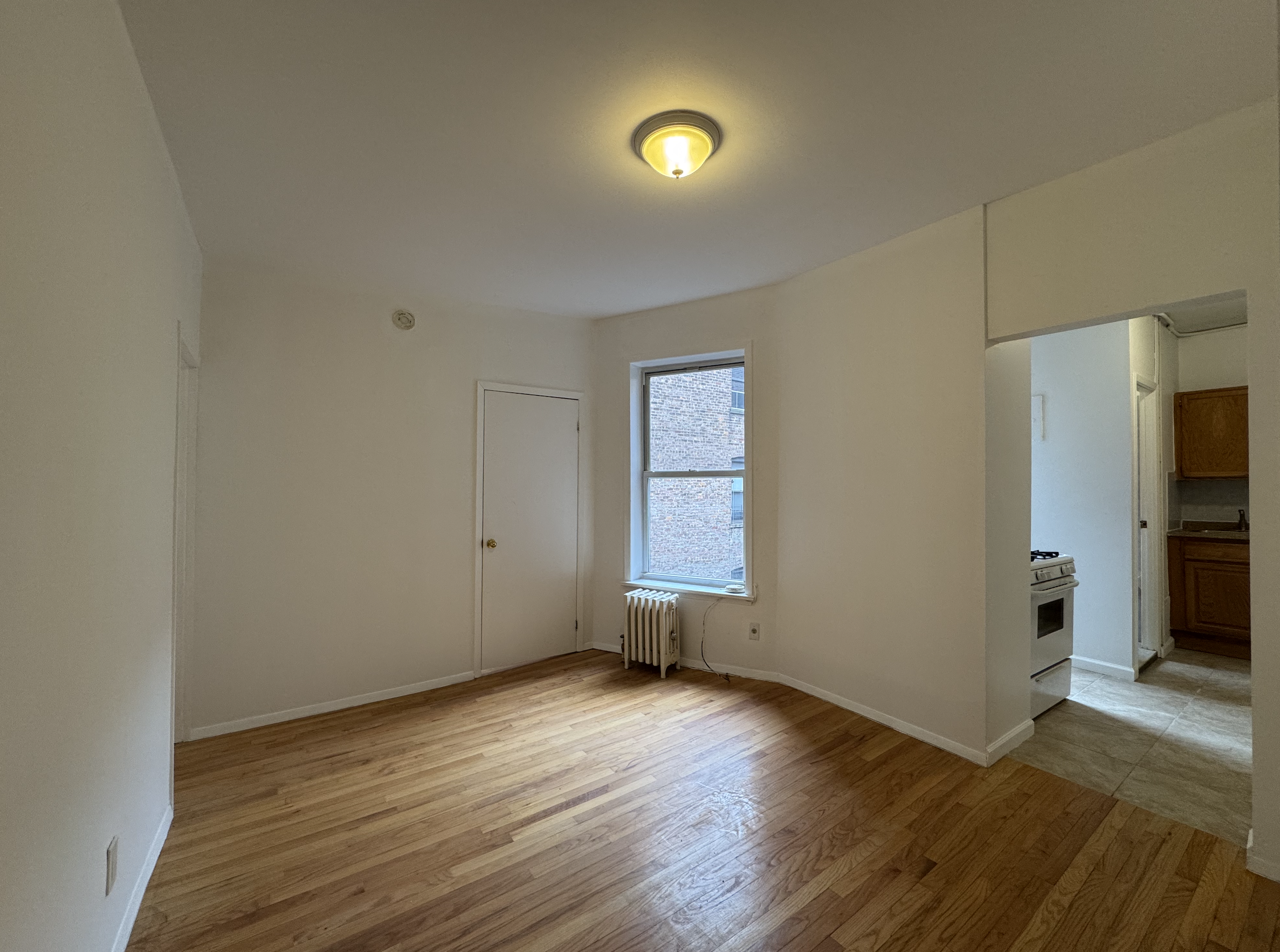 451 West 44th Street, Unit 63 Manhattan, NY 10036 - Photo 11 of 33 an empty room with wooden floor and windows