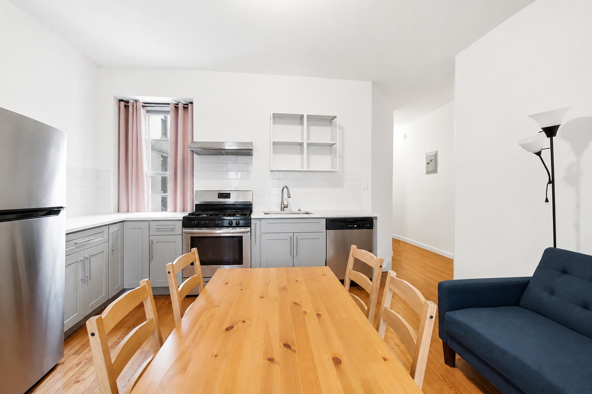 a kitchen with a refrigerator a stove a sink dishwasher with a dining table and chair