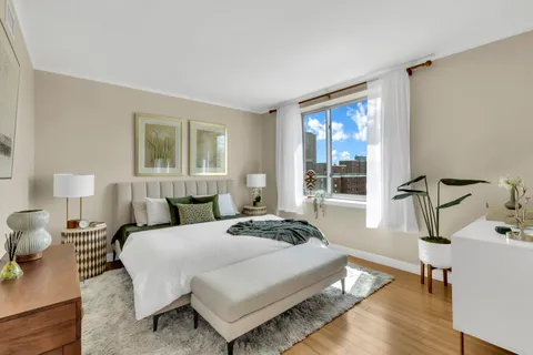 a bedroom with a bed a table and windows