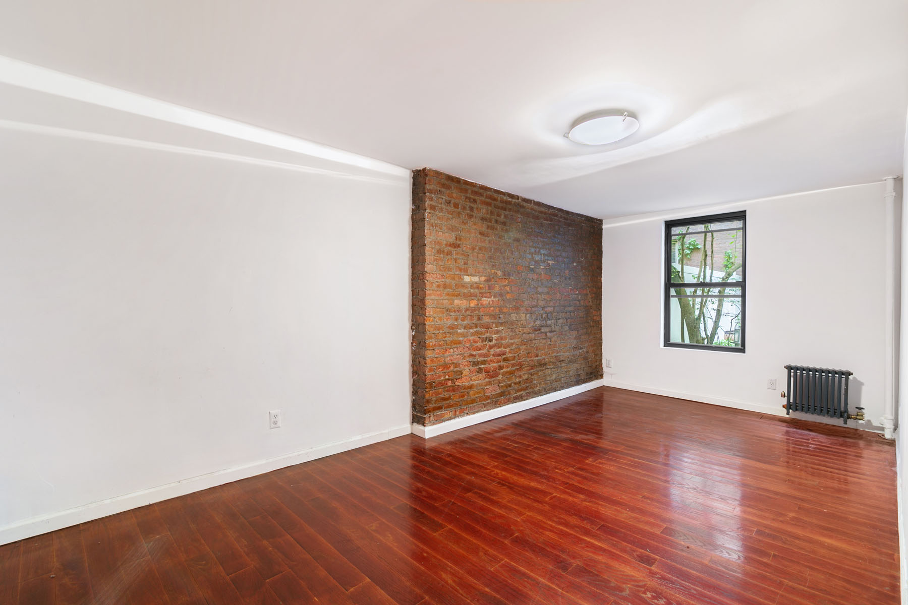 54 Jane Street Manhattan, NY 10014 - Photo 19 of 26 an empty room with wooden floor and windows