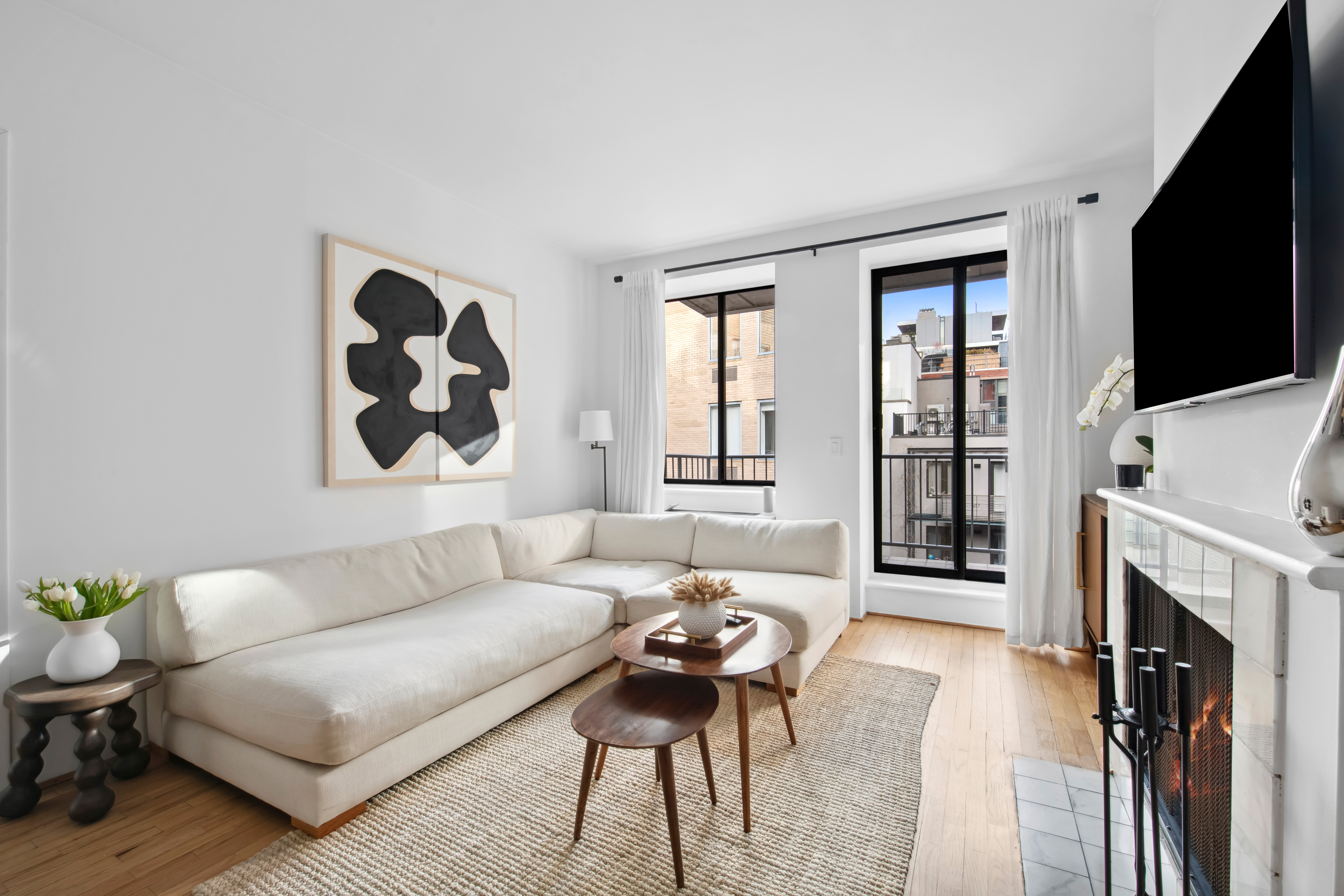167 Perry Street, Unit 5H Manhattan, NY 10014 - Photo 2 of 8 a living room with furniture a fireplace and a flat screen tv