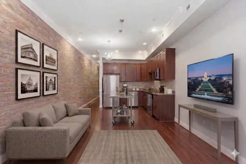 a living room with stainless steel appliances furniture and a kitchen view