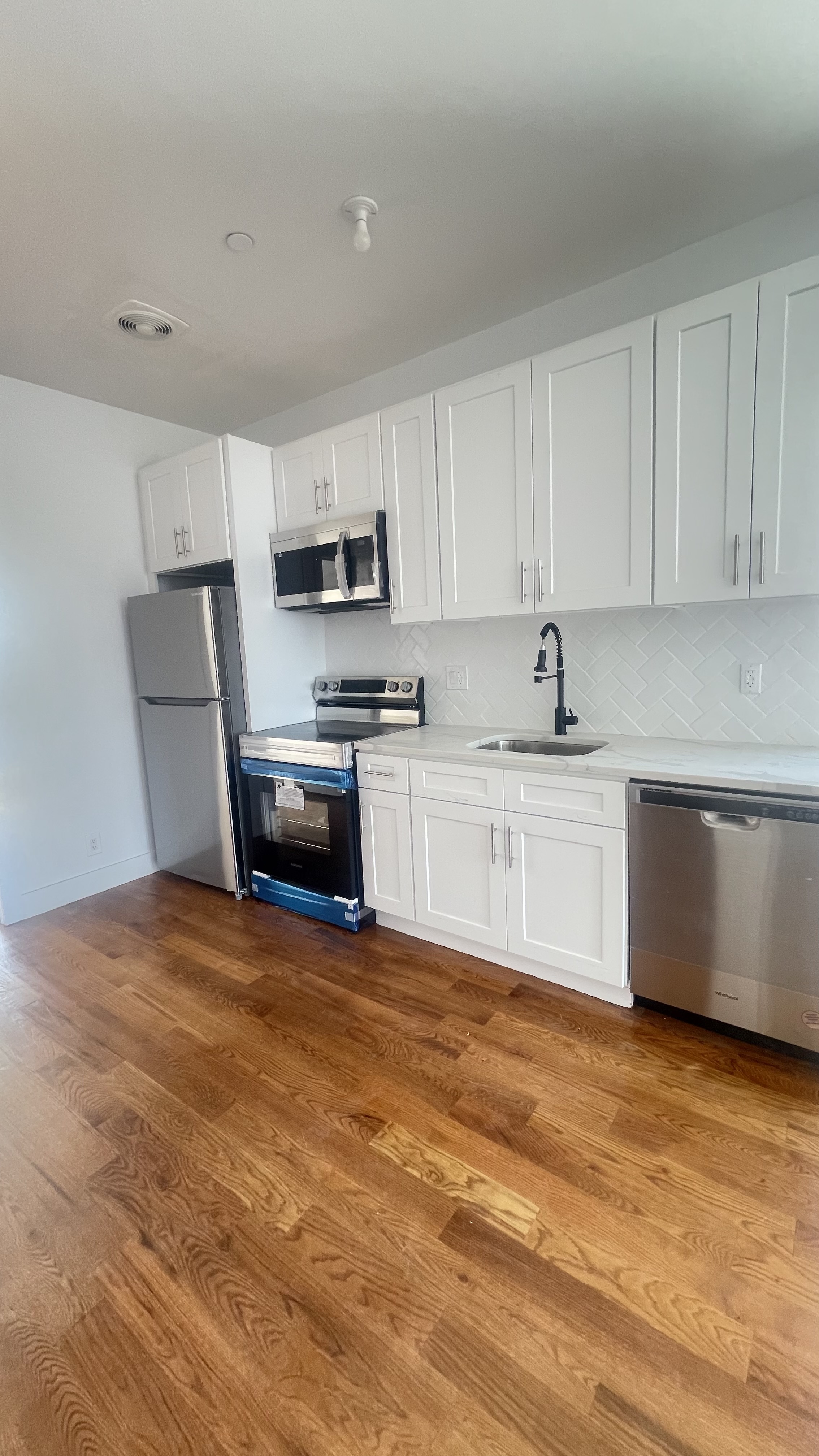 1010 Gates Avenue, Unit 6C Brooklyn, NY 11221 - Photo 2 of 9 a large white kitchen with a sink a stove a microwave and cabinets