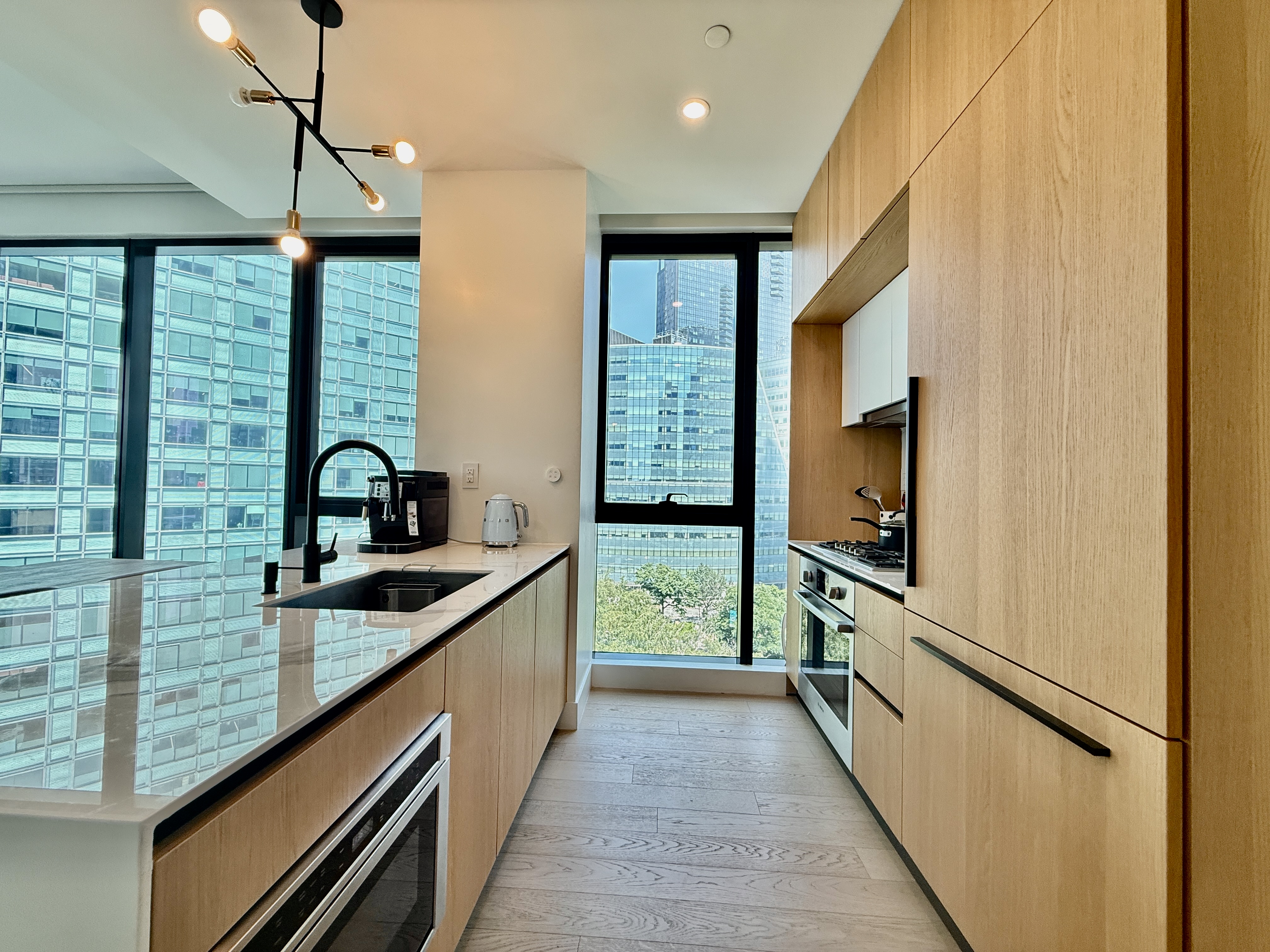 4507 Court Square, Unit 8D Queens, NY 11101 - Photo 6 of 28 a kitchen with kitchen island a counter top space a sink a refrigerator and wooden floor