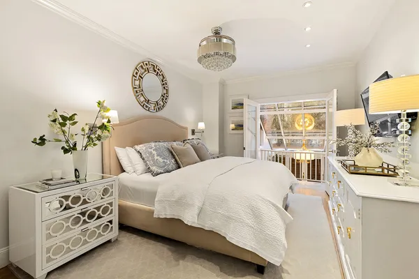 a bedroom with a bed a mirror on the dresser and a chandelier