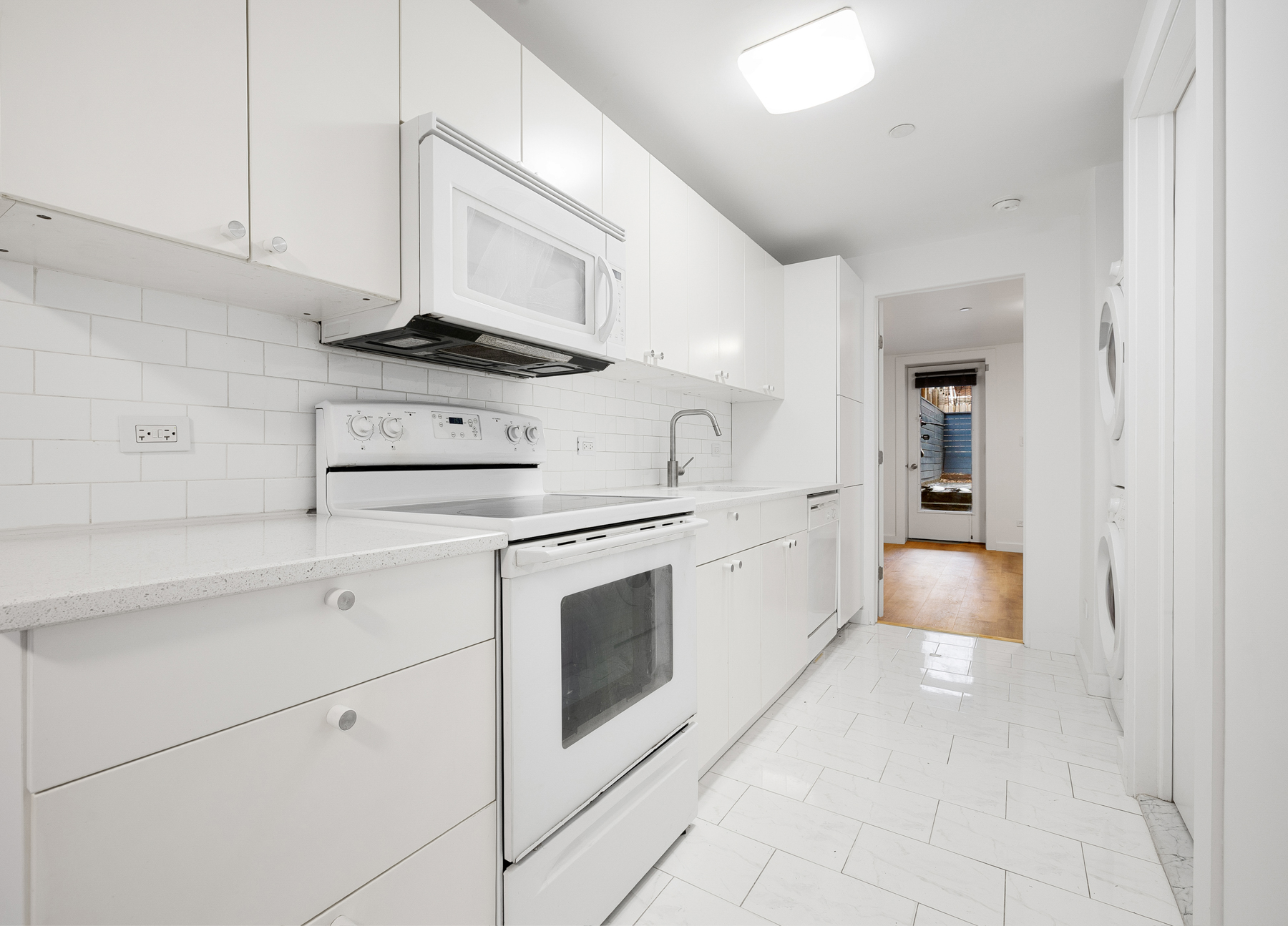 63 Putnam Avenue Brooklyn, NY 11238 - Photo 8 of 11 a kitchen with white cabinets and white appliances