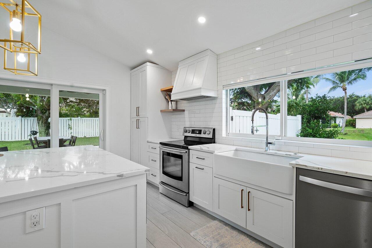 1182 Canoe Point Delray Beach, FL 33444 - Photo 12 of 46 a kitchen with kitchen island a sink stove and cabinets