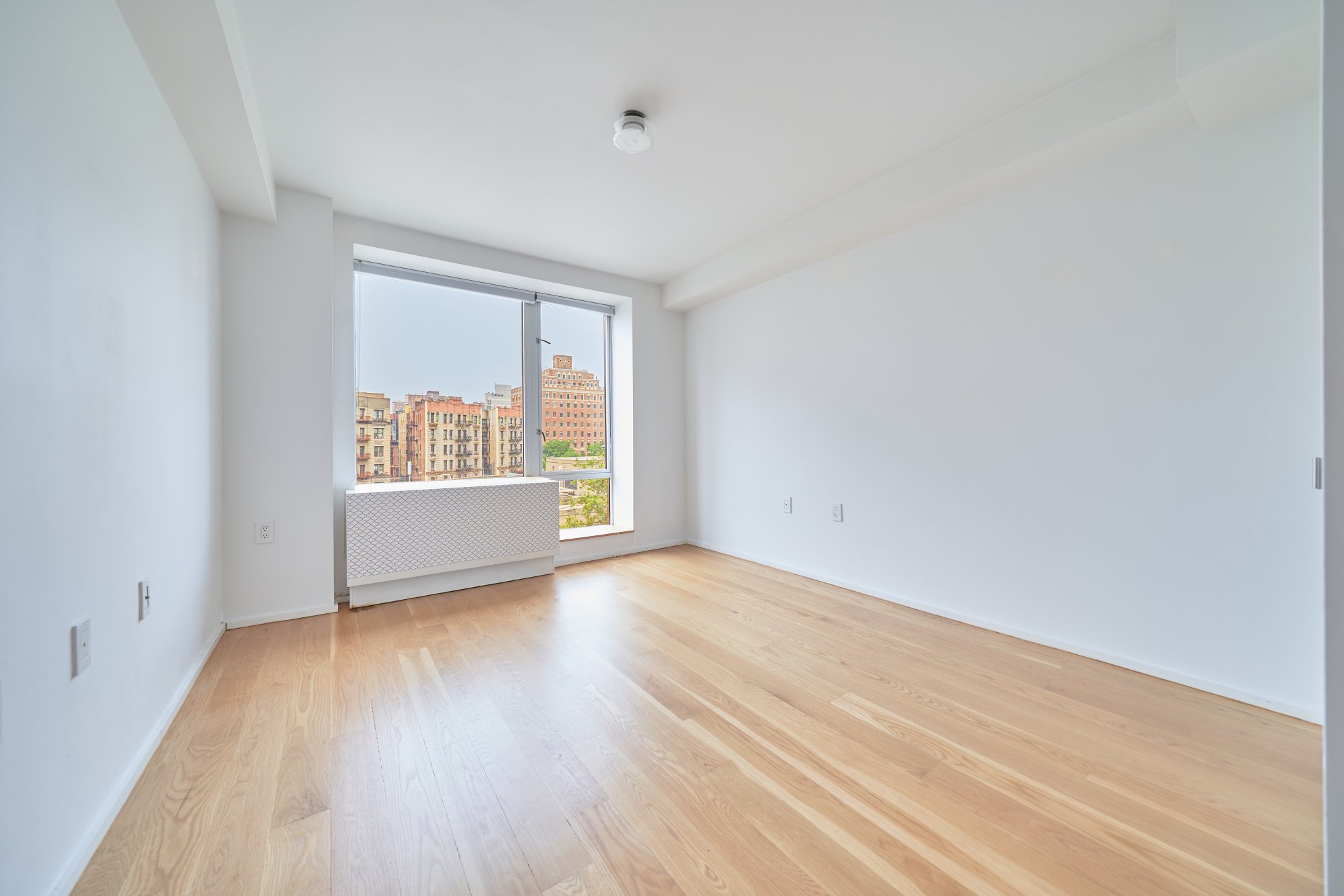 2280 Frederick Douglass Boulevard, Unit 5D Manhattan, NY 10027 - Photo 9 of 22 an empty room with wooden floor and windows