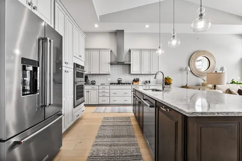 a kitchen with stainless steel appliances granite countertop a sink refrigerator and cabinets
