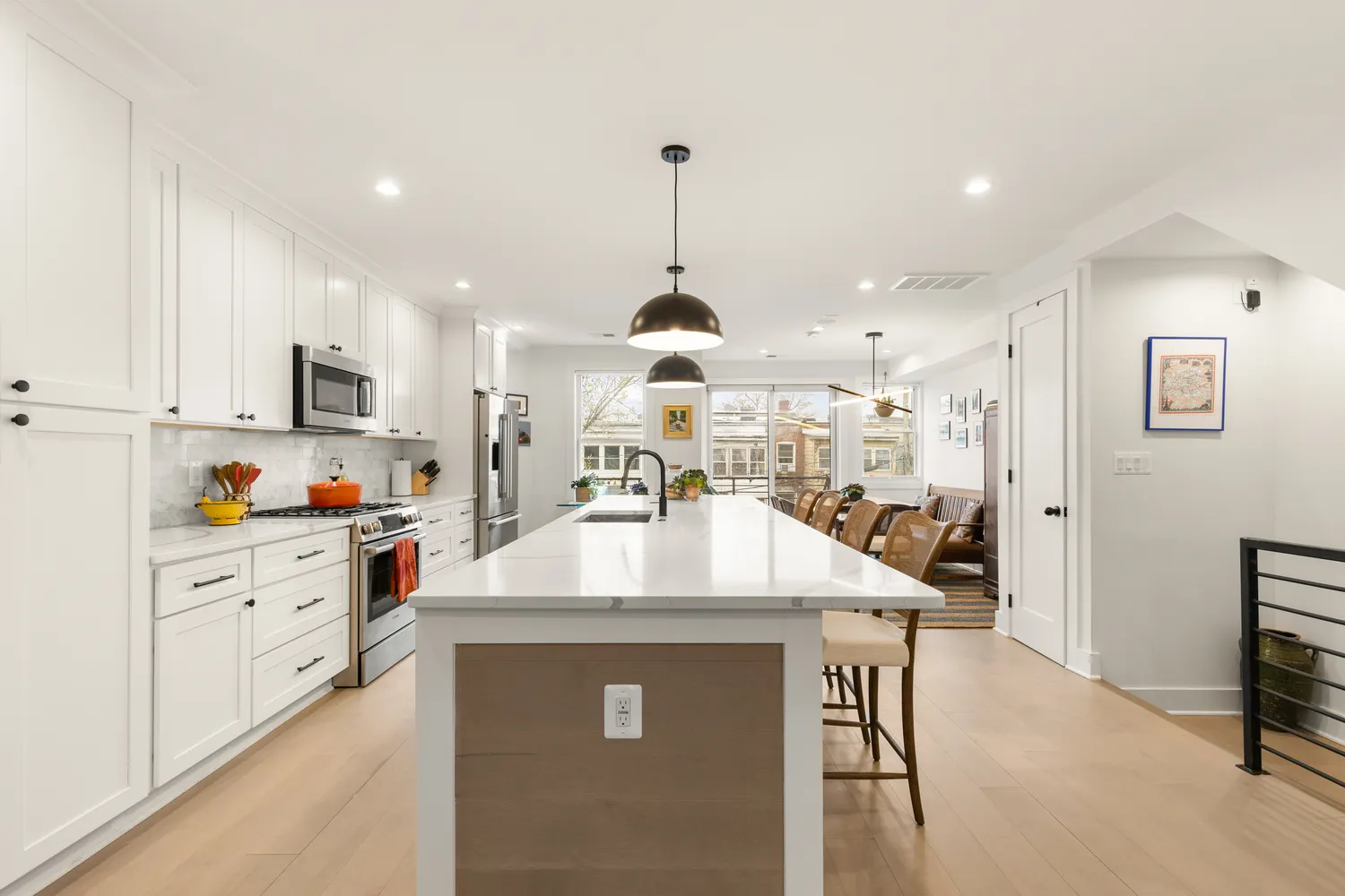 a kitchen with stainless steel appliances kitchen island granite countertop a stove a sink a refrigerator and white cabinets with wooden floor