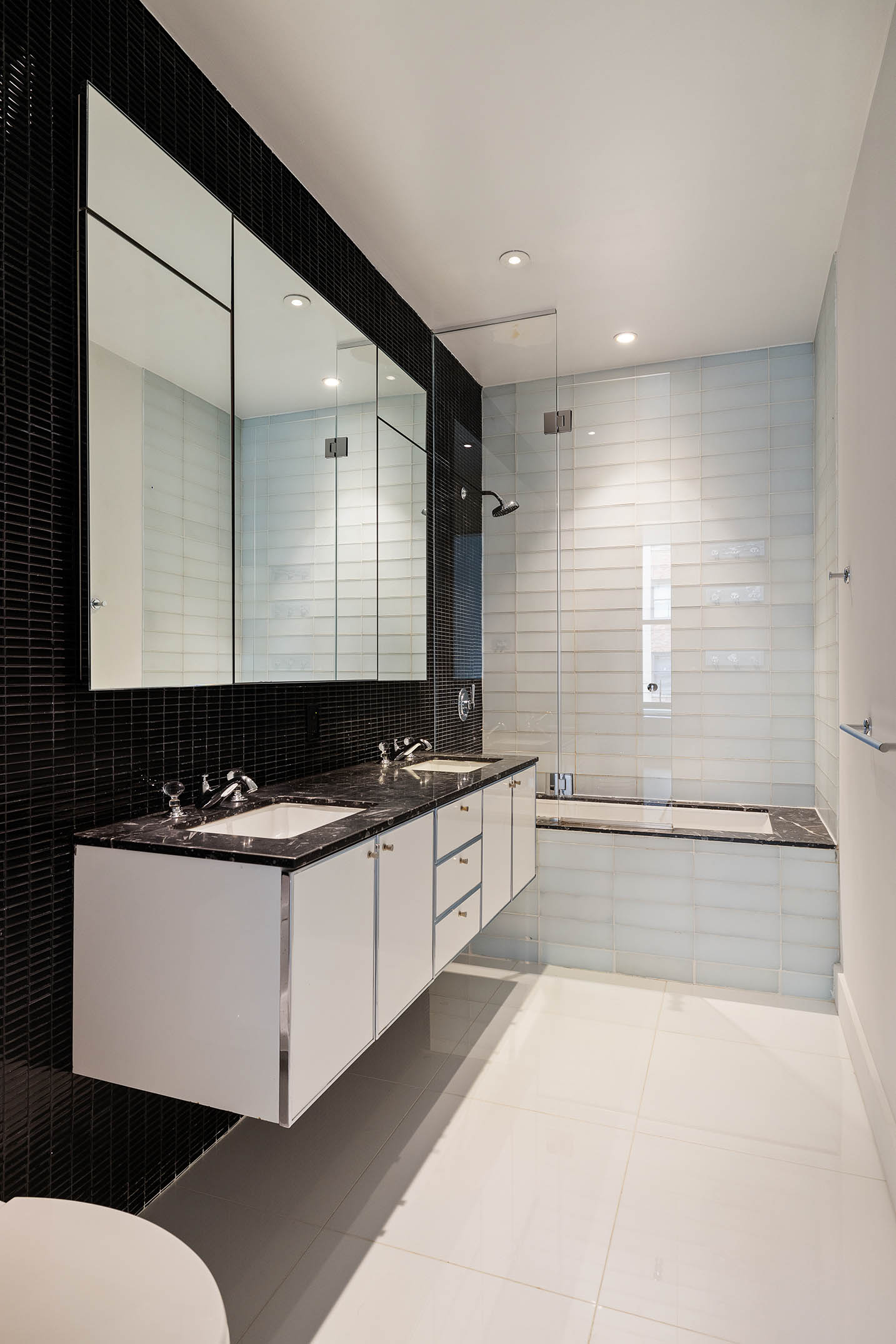 25 Broad Street, Unit 16I Manhattan, NY 10004 - Photo 10 of 23 a large bathroom with a double vanity sink a mirror and a bathtub