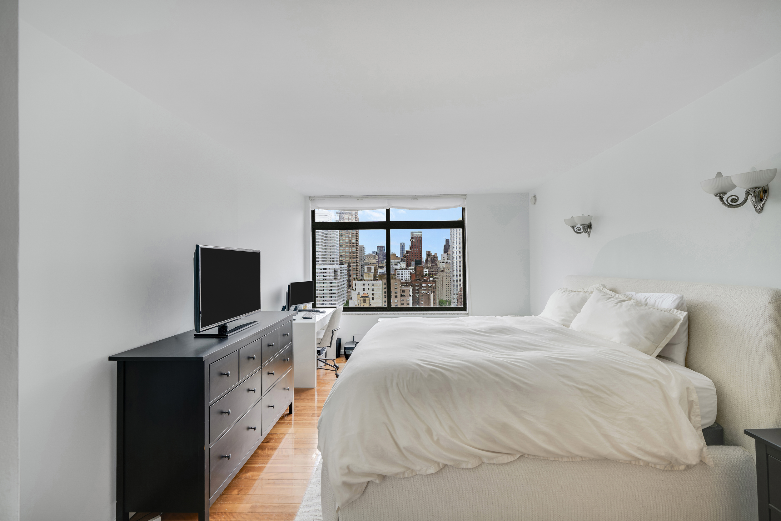 400 East 70th Street, Unit 2402 Manhattan, NY 10021 - Photo 8 of 18 a bedroom with a bed and a flat tv screen on a dresser