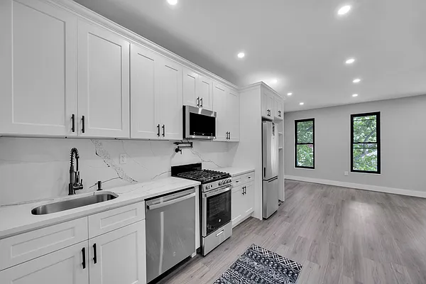 30 Marconi Place, Unit 2 Brooklyn, NY 11233 - Photo 4 of 11 a kitchen with granite countertop white cabinets and stainless steel appliances