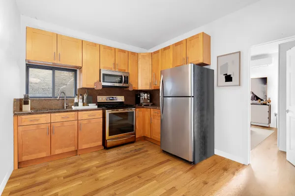 a kitchen with granite countertop stainless steel appliances a refrigerator cabinets and a window