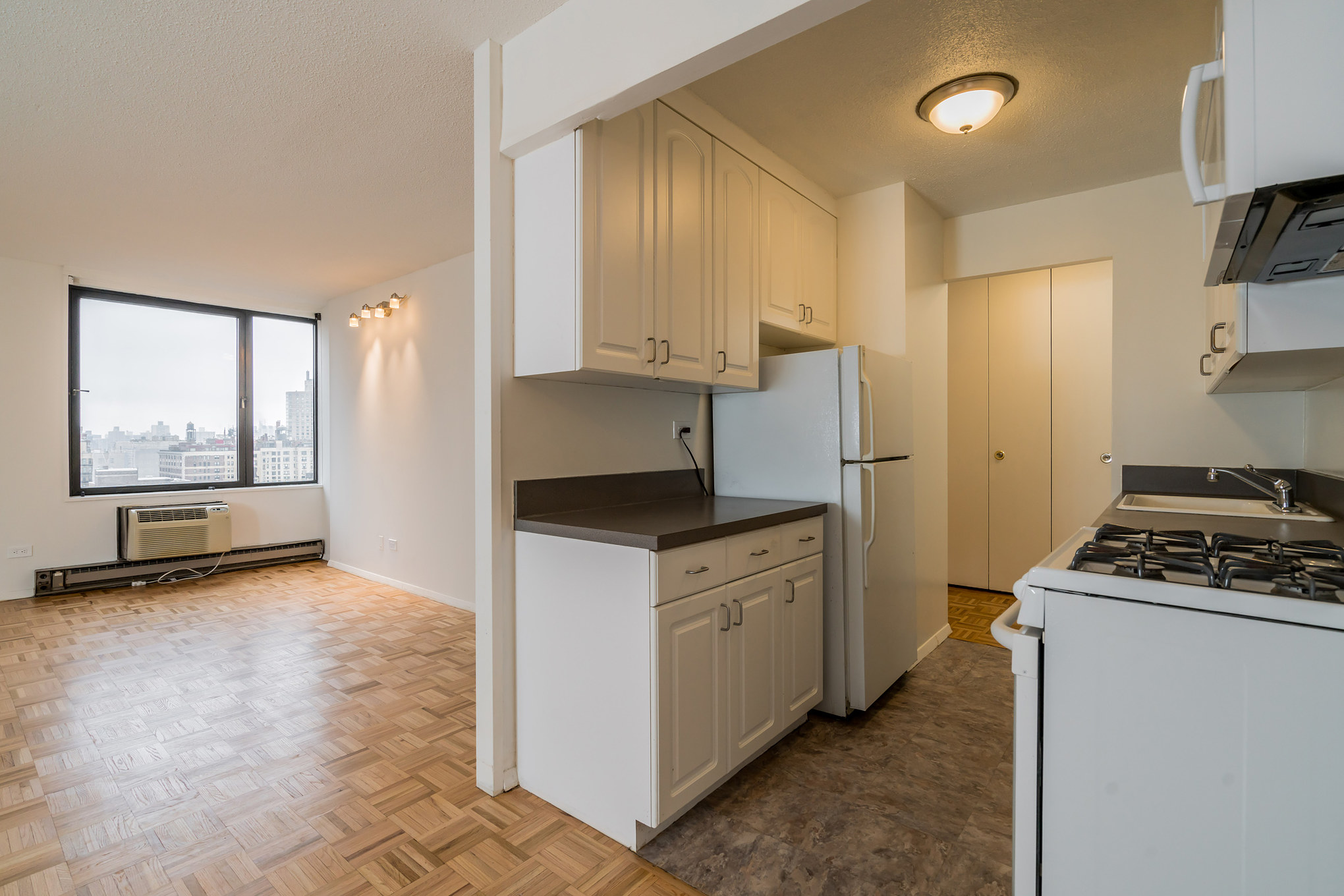 1641 3rd Avenue, Unit 24D Manhattan, NY 10128 - Photo 3 of 7 a kitchen with stainless steel appliances granite countertop a stove a refrigerator and a more cabinets