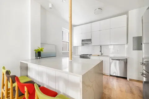 a kitchen with stainless steel appliances granite countertop a sink a stove and white cabinets with wooden floor