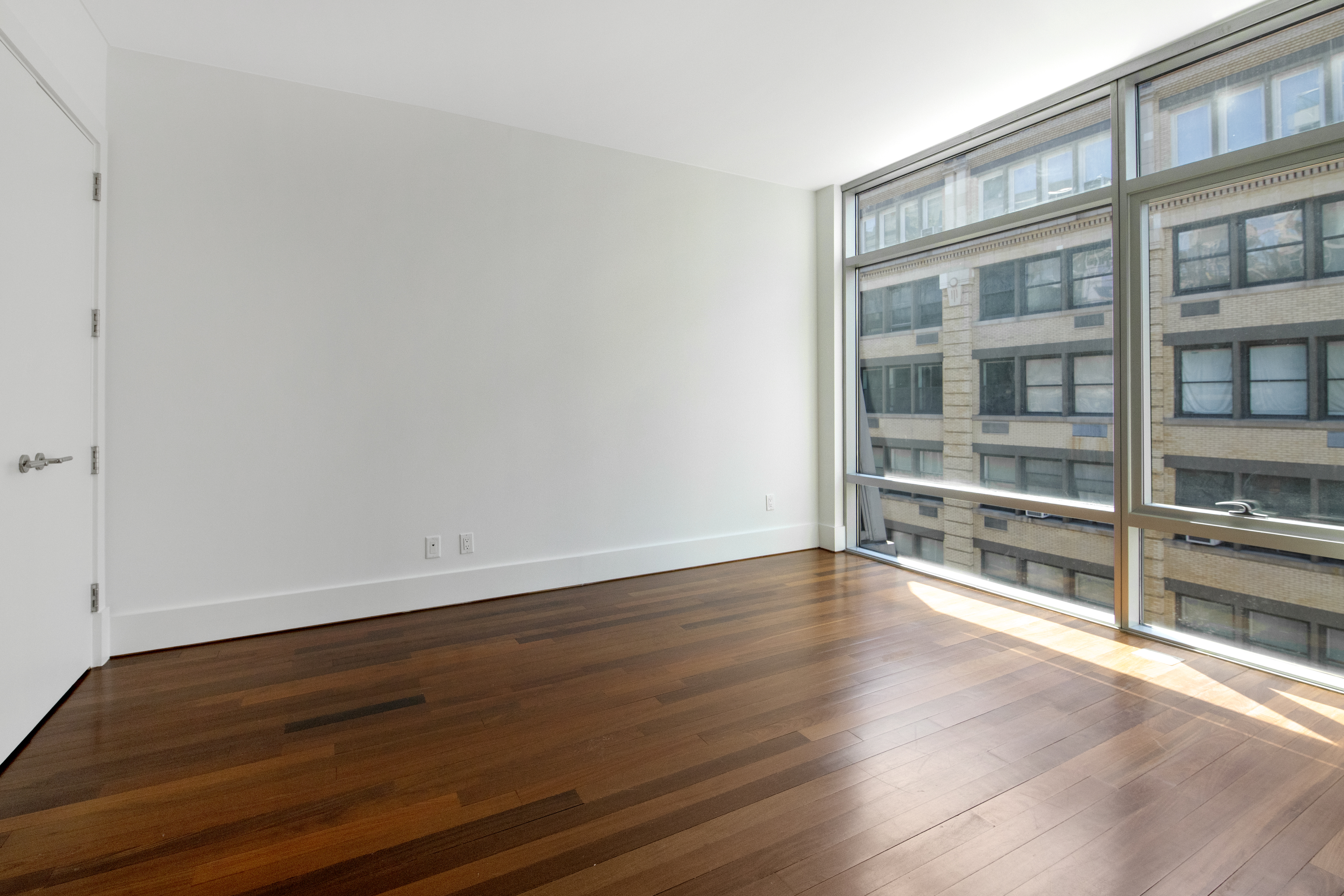 165 West 18th Street, Unit 8B Manhattan, NY 10011 - Photo 6 of 9 a view of an empty room with wooden floor and a window