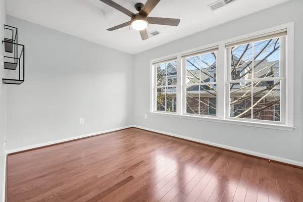 a view of an empty room with wooden floor and a window
