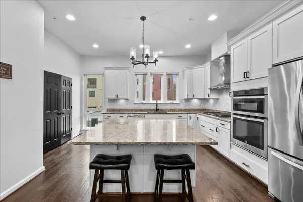 a large kitchen with granite countertop a large counter top appliances and cabinets