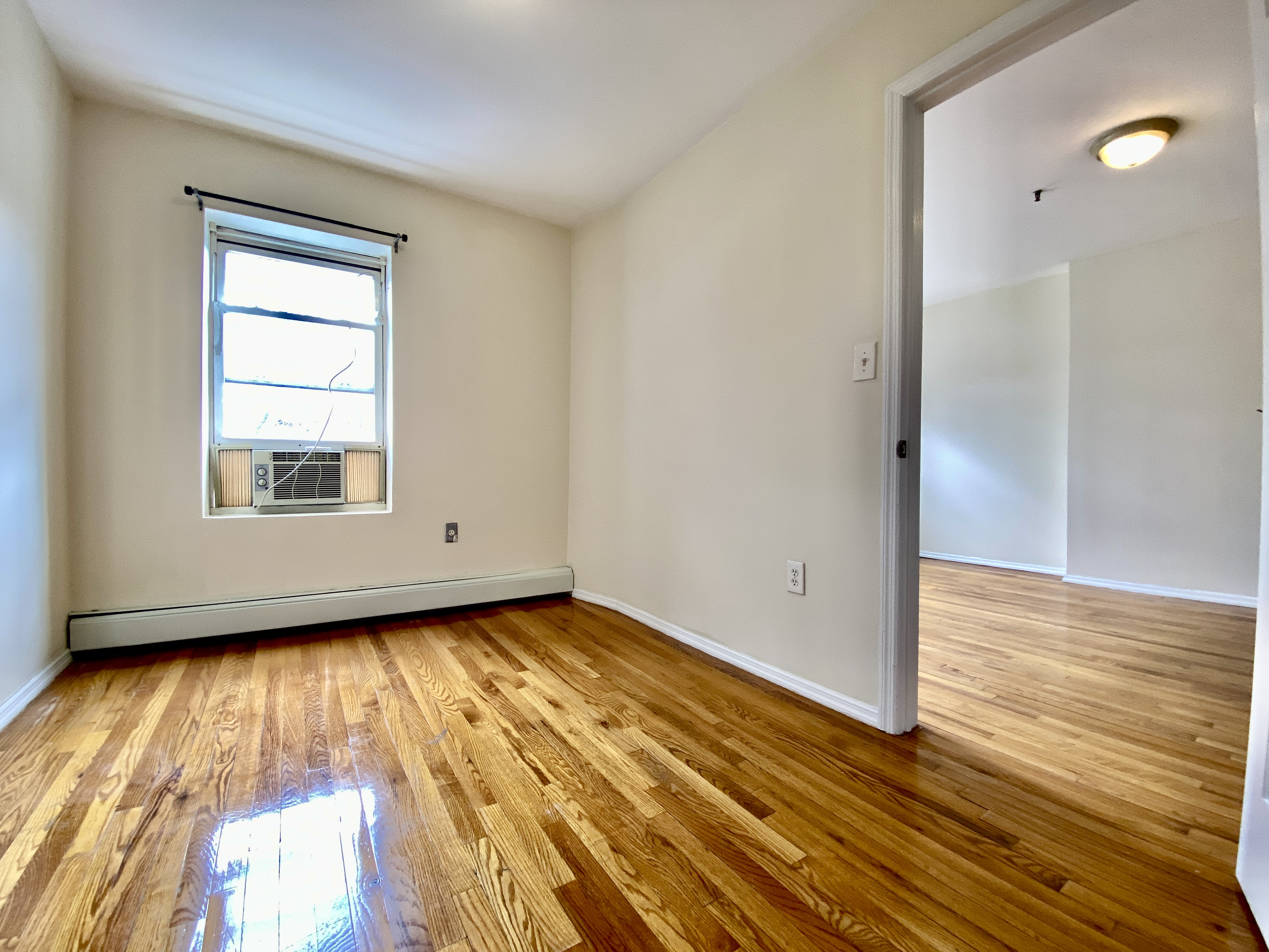 373 Gates Avenue, Unit 4 Brooklyn, NY 11216 - Photo 9 of 10 a view of an empty room with wooden floor and a window