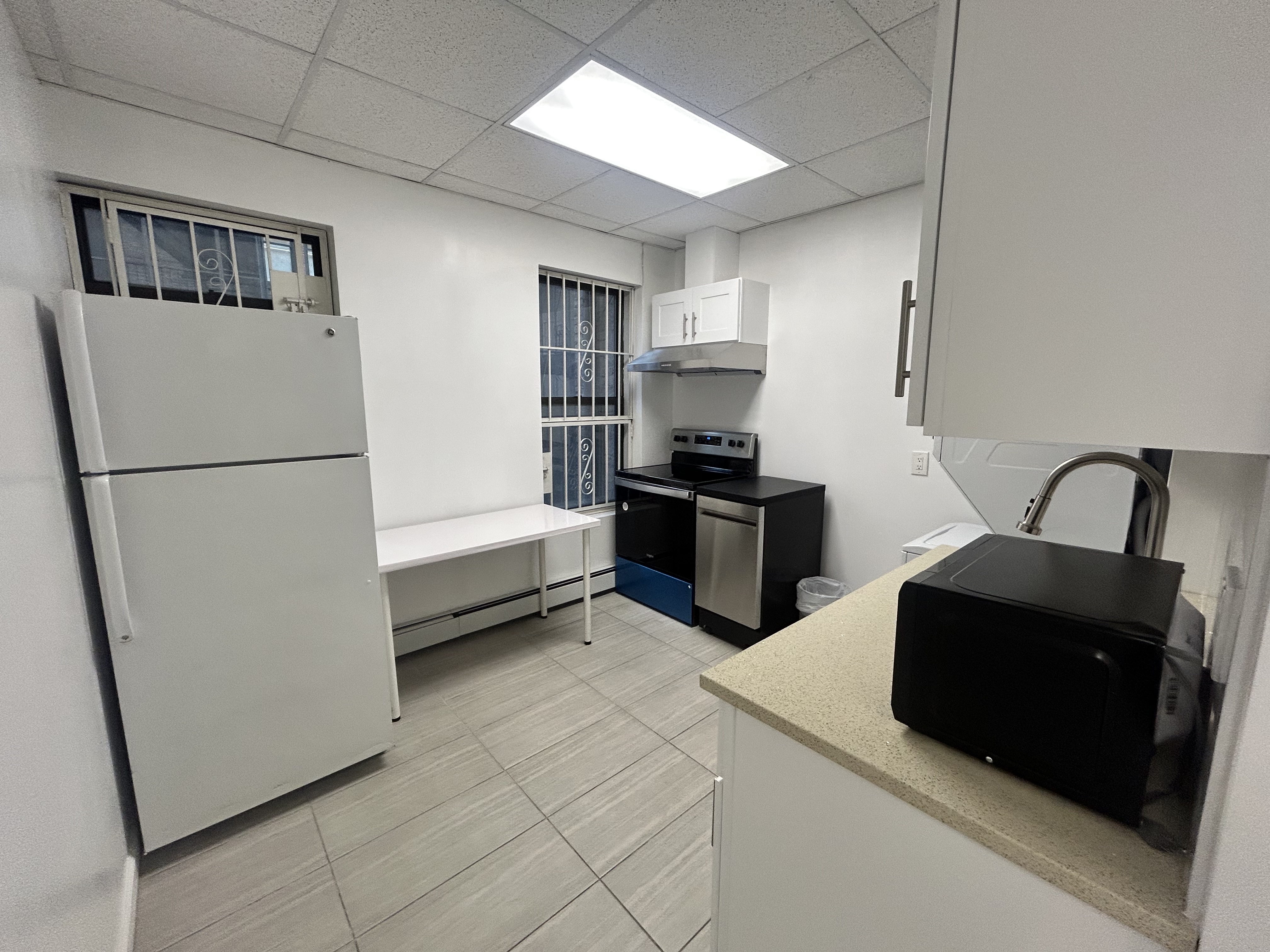 47 West 37th Street, Unit 4 Manhattan, NY 10018 - Photo 2 of 7 a kitchen with stainless steel appliances a refrigerator sink and white cabinets