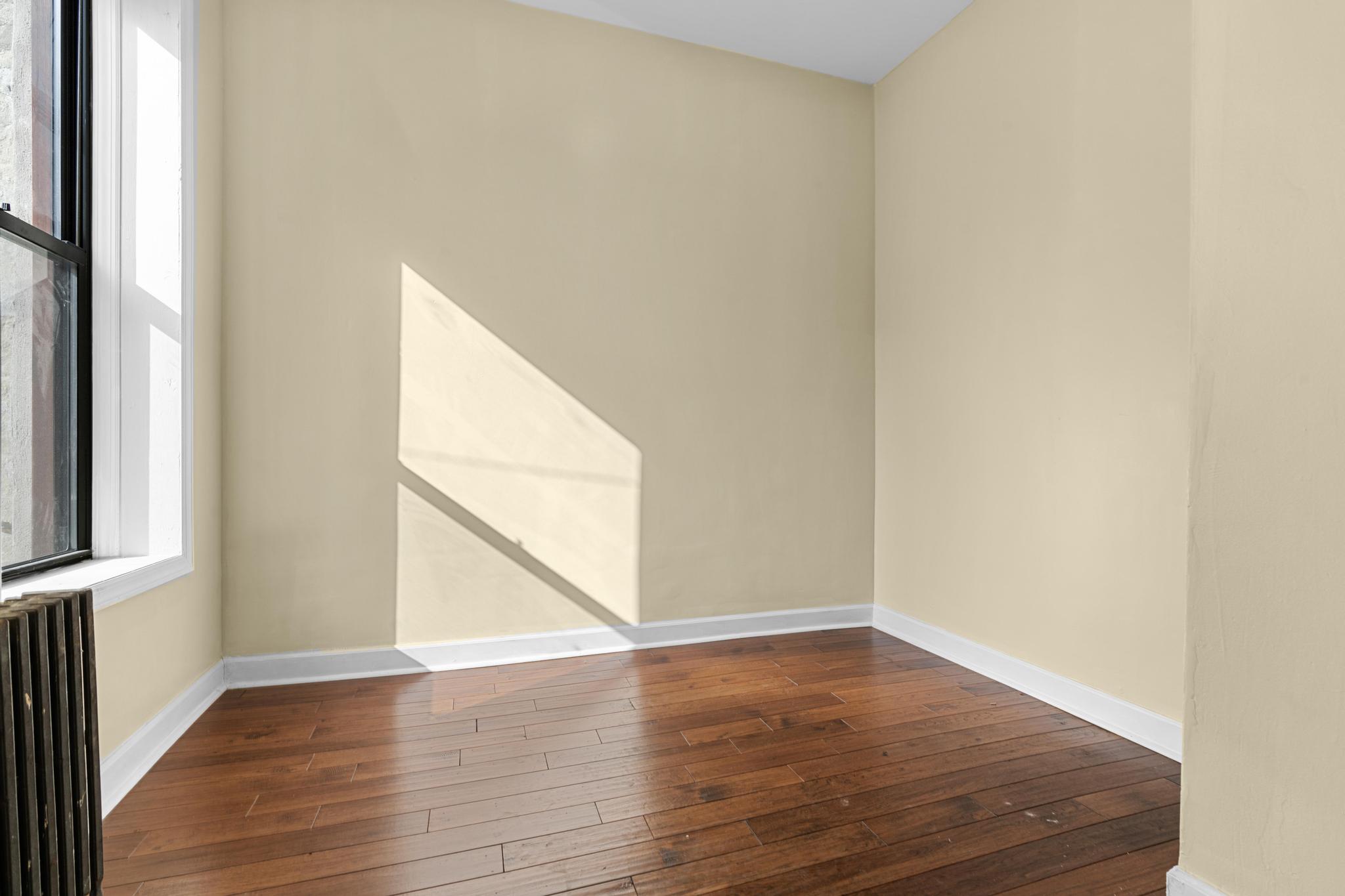 1328 Herkimer Street, Unit 1 Brooklyn, NY 11233 - Photo 7 of 9 a view of an empty room with wooden floor and a window