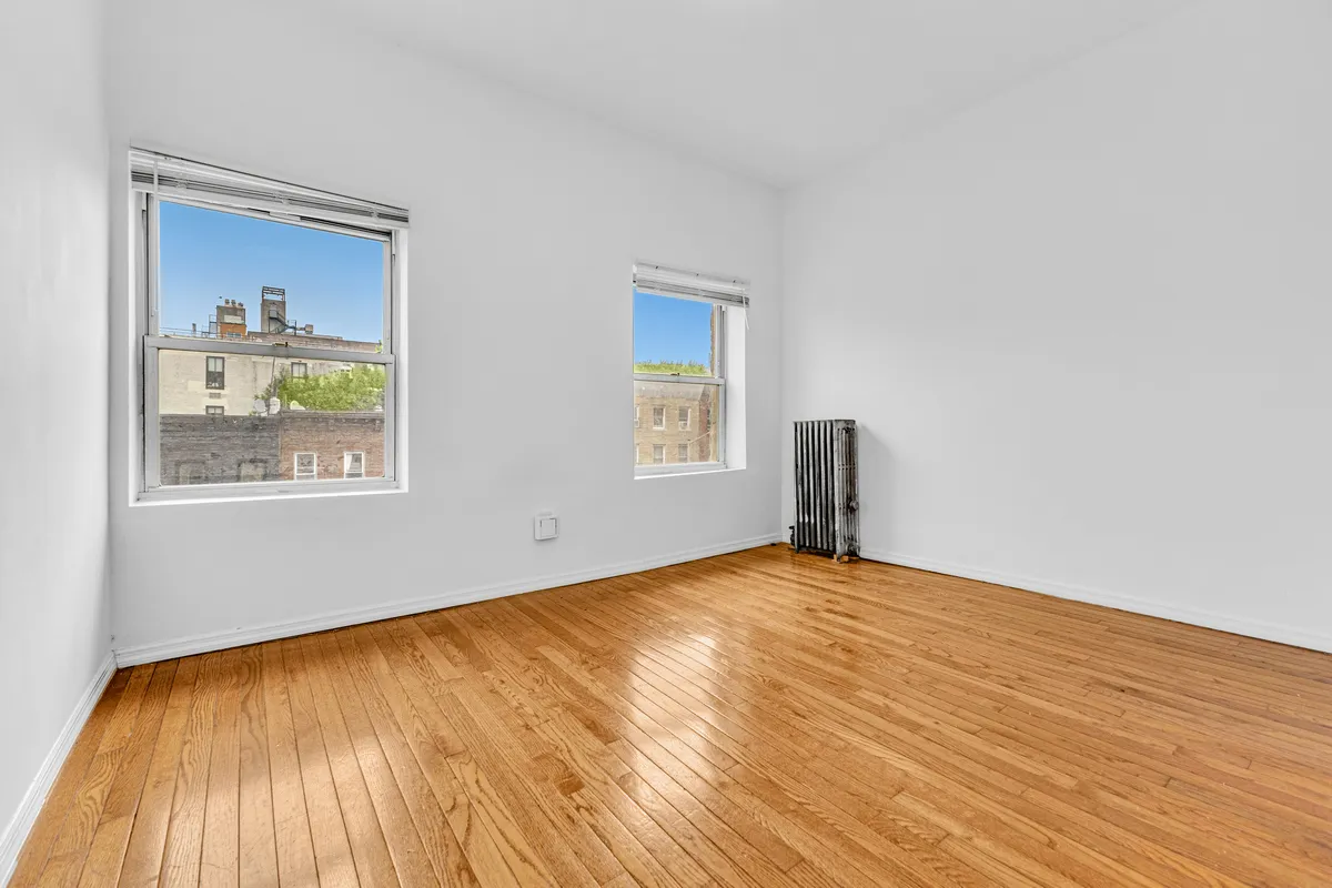 a view of an empty room with window and wooden floor
