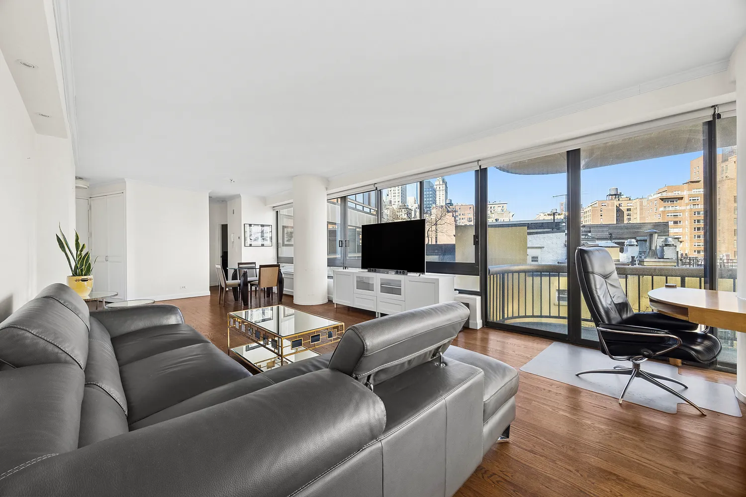a living room with furniture floor to ceiling window and a flat screen tv