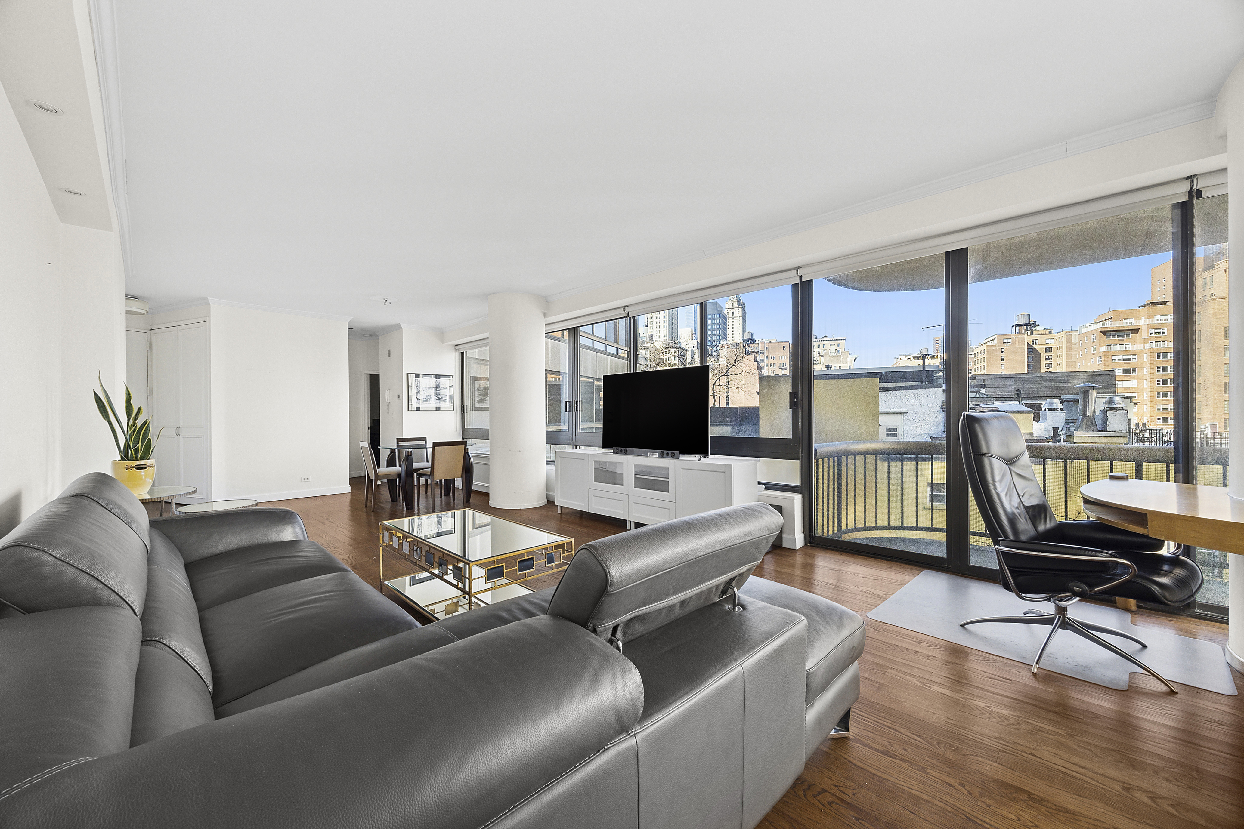 167 East 61st Street, Unit 7D Manhattan, NY 10065 - Photo 2 of 8 a living room with furniture floor to ceiling window and a flat screen tv