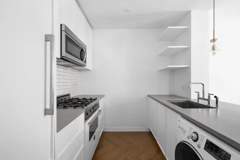 a kitchen with granite countertop a sink and a stove top oven with wooden floor