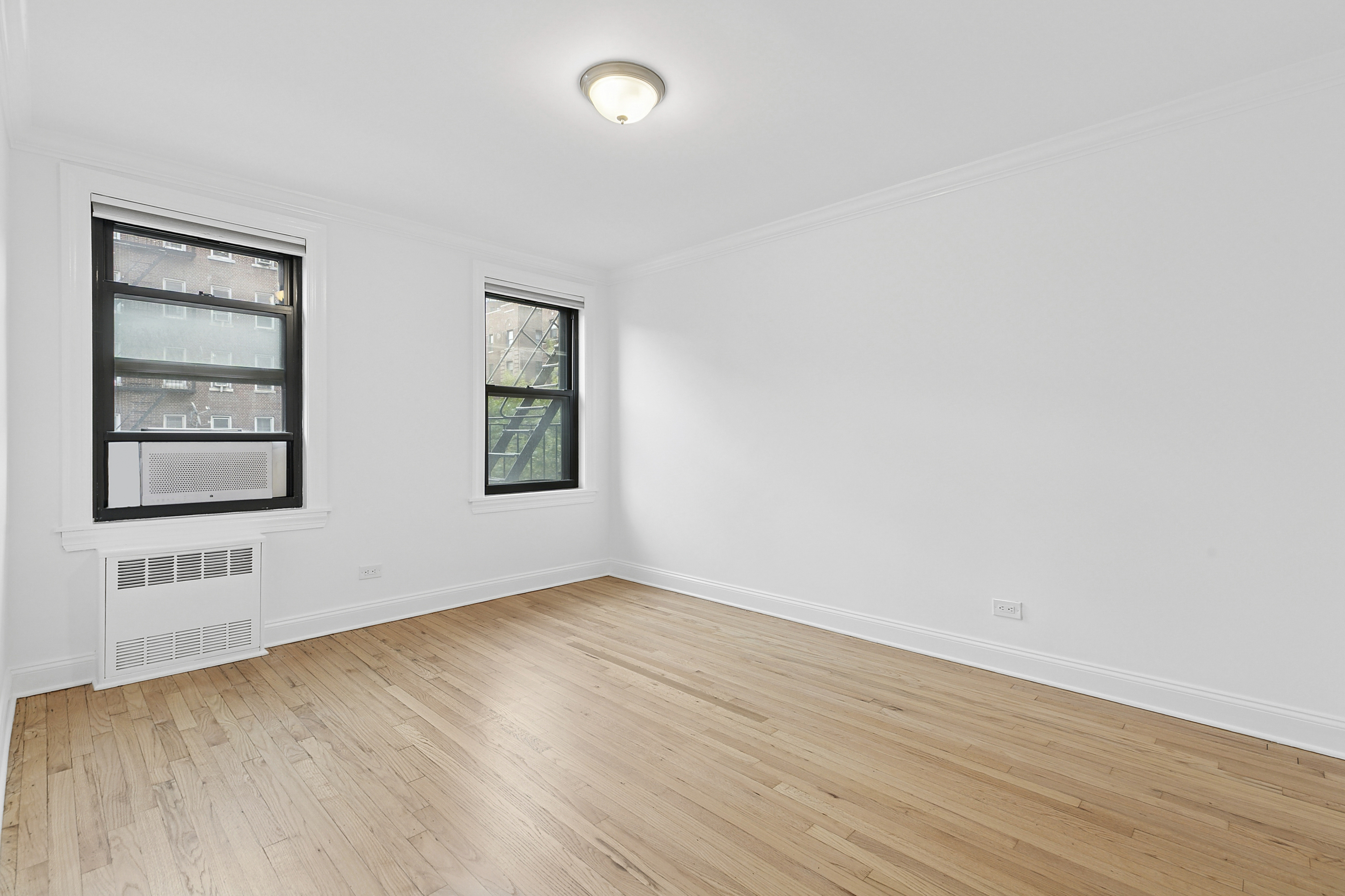 4501 Broadway, Unit 4G Manhattan, NY 10040 - Photo 5 of 7 an empty room with wooden floor and windows