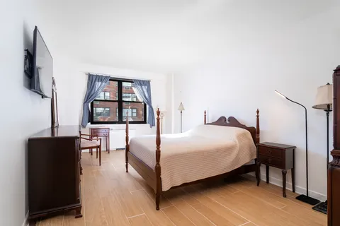 a bedroom with a bed window and a flat screen tv