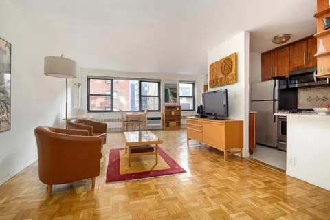 a living room with furniture a rug kitchen view and a window