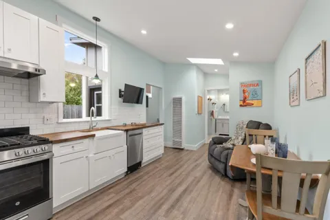 a kitchen with stainless steel appliances granite countertop a stove top oven a sink a dining table and chairs