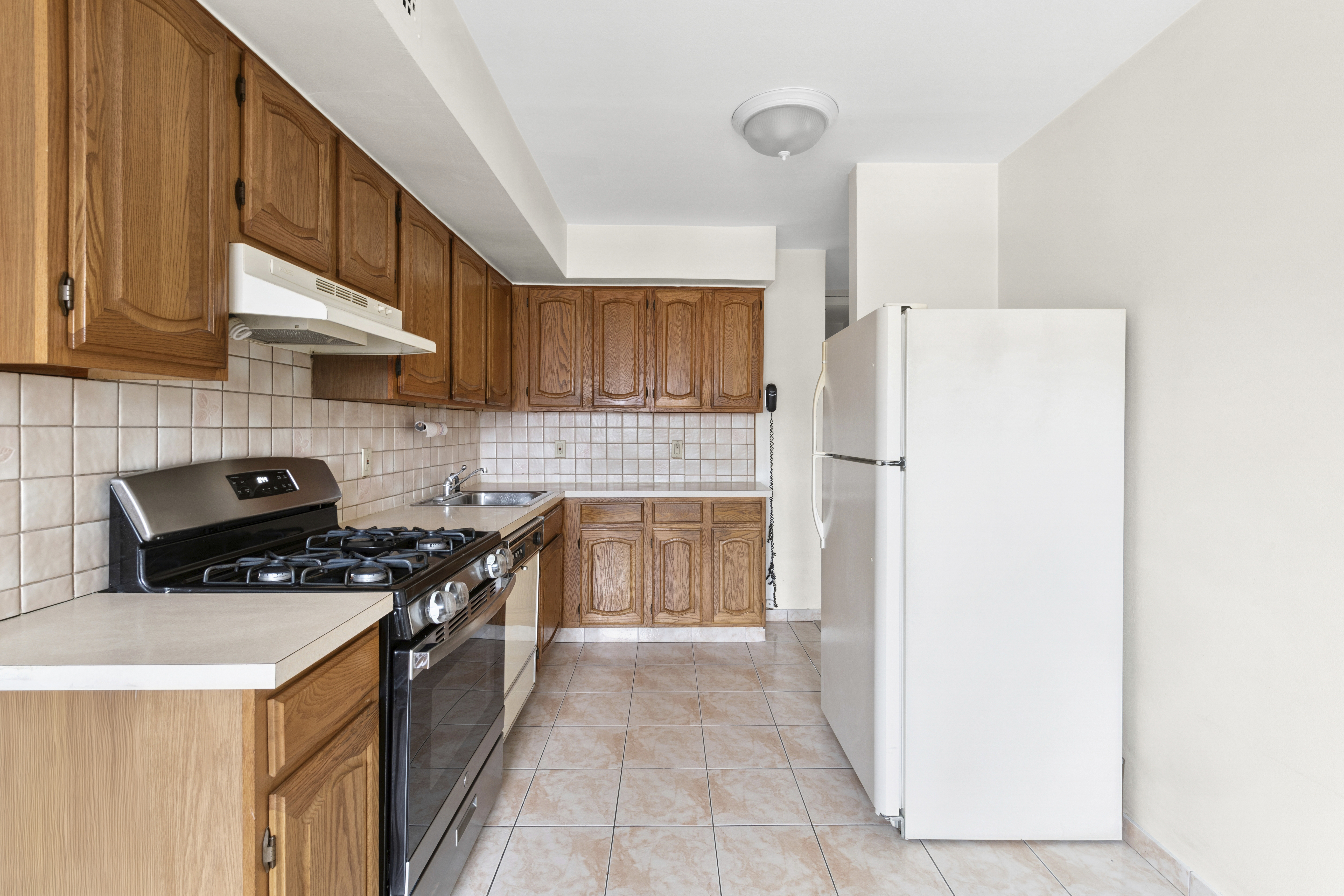 25-36 72nd Street Queens, NY 11370 - Photo 4 of 17 a kitchen with a stove a refrigerator and a cabinets