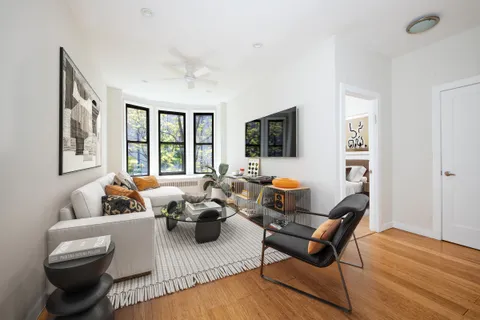 a living room with furniture floor to ceiling window and a flat screen tv