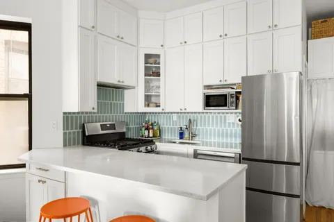 a kitchen with stainless steel appliances a refrigerator sink and white cabinets