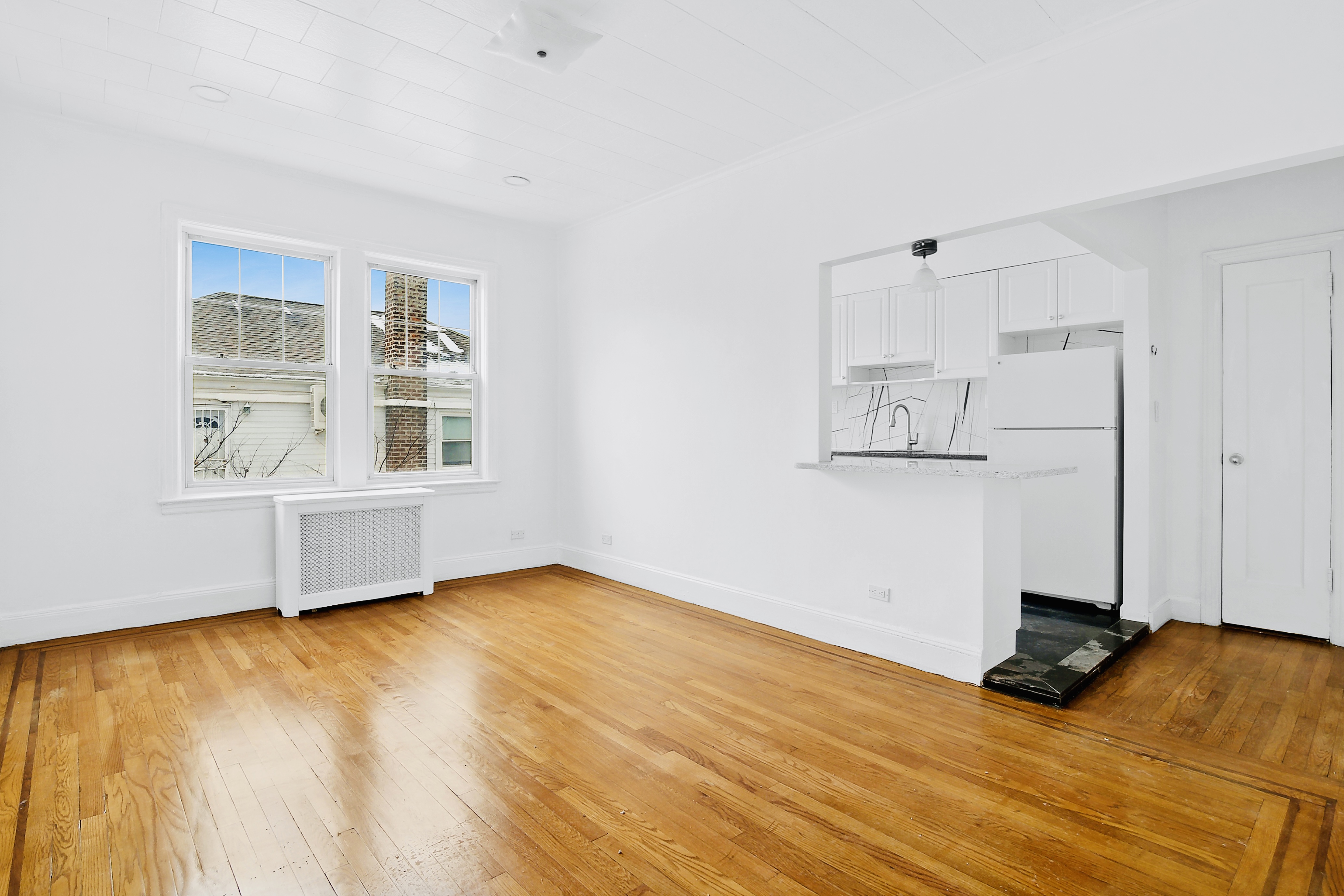 a view of an empty room with a window and wooden floor