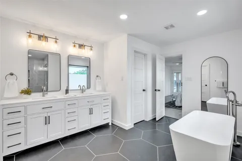 a spacious bathroom with a double vanity sink a mirror and a bathtub