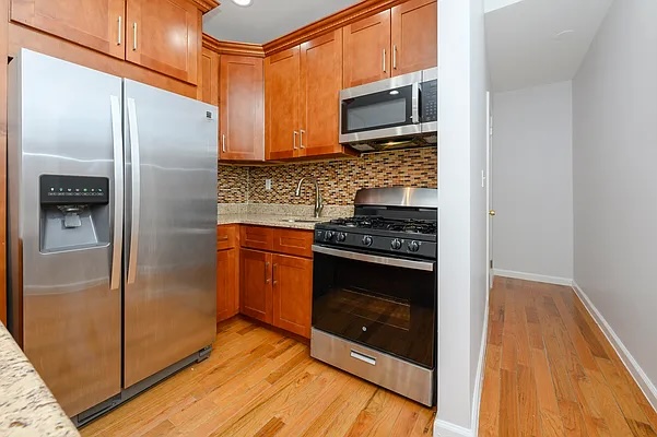 a kitchen with granite countertop a refrigerator and a stove top oven