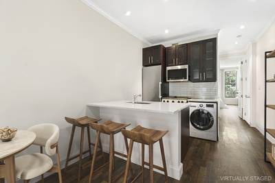 106 Bedford Avenue, Unit 3L Brooklyn, NY 11249 - Photo 2 of 7 a kitchen with stainless steel appliances kitchen island granite countertop a table chairs and microwave