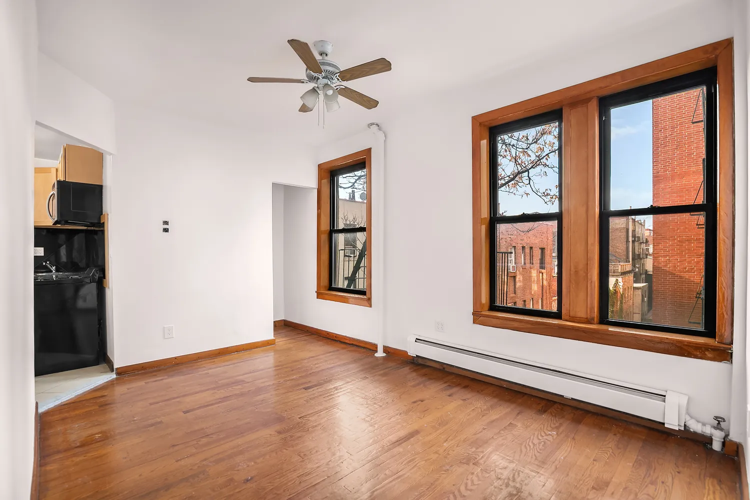 a view of an empty room with a window and wooden floor