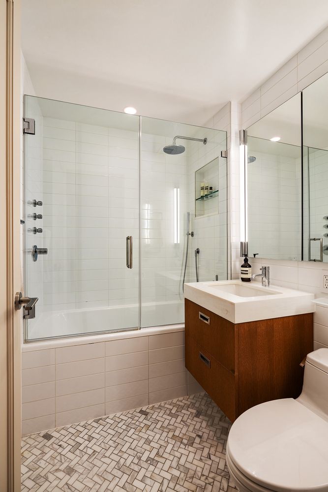 a bathroom with a bathtub shower sink mirror and toilet
