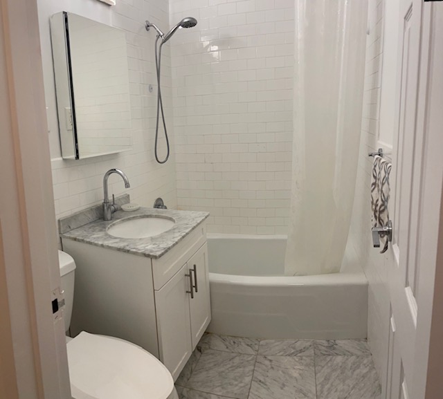150 West End Avenue, Unit 2G Manhattan, NY 10023 - Photo 5 of 10 a bathroom with a granite countertop toilet a sink and a bathtub