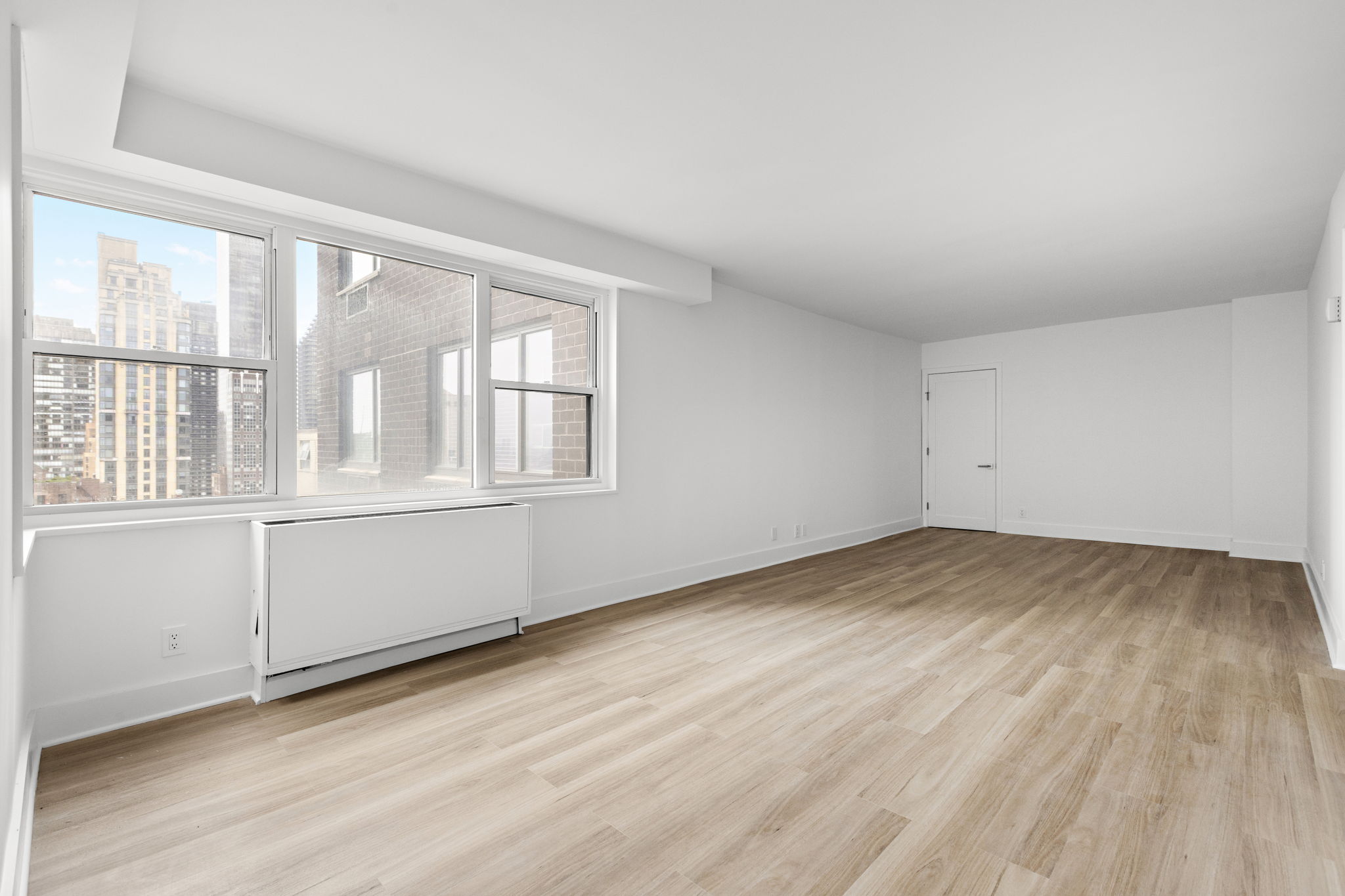 400 East 54th Street, Unit 19H Manhattan, NY 10022 - Photo 2 of 19 an empty room with wooden floor and windows