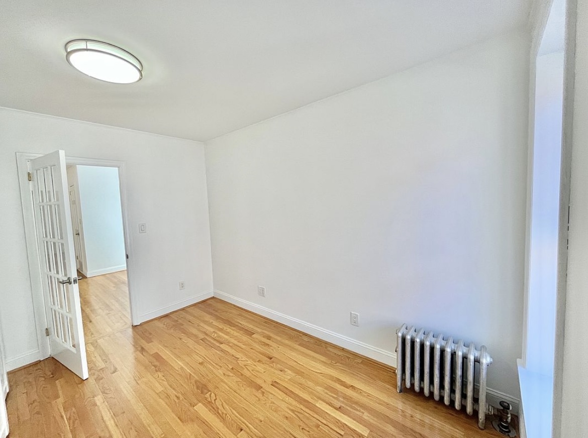 80 East 7th Street, Unit 4C Manhattan, NY 10003 - Photo 5 of 7 a view of an empty room with wooden floor and a window