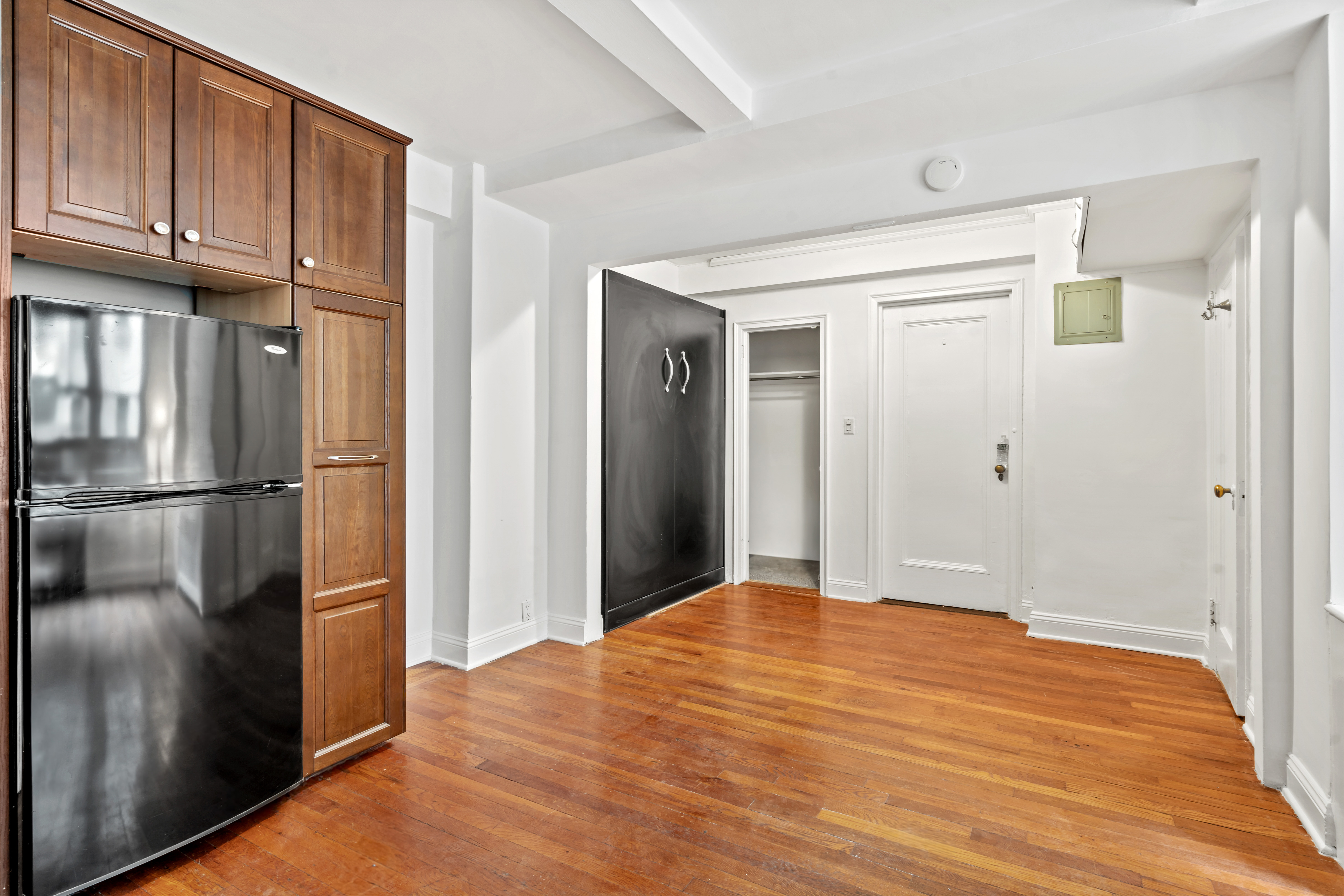 155 East 49th Street, Unit 8C Manhattan, NY 10017 - Photo 6 of 10 a view of an empty room with wooden floor and a kitchen
