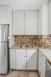 a kitchen with granite countertop white cabinets and refrigerator