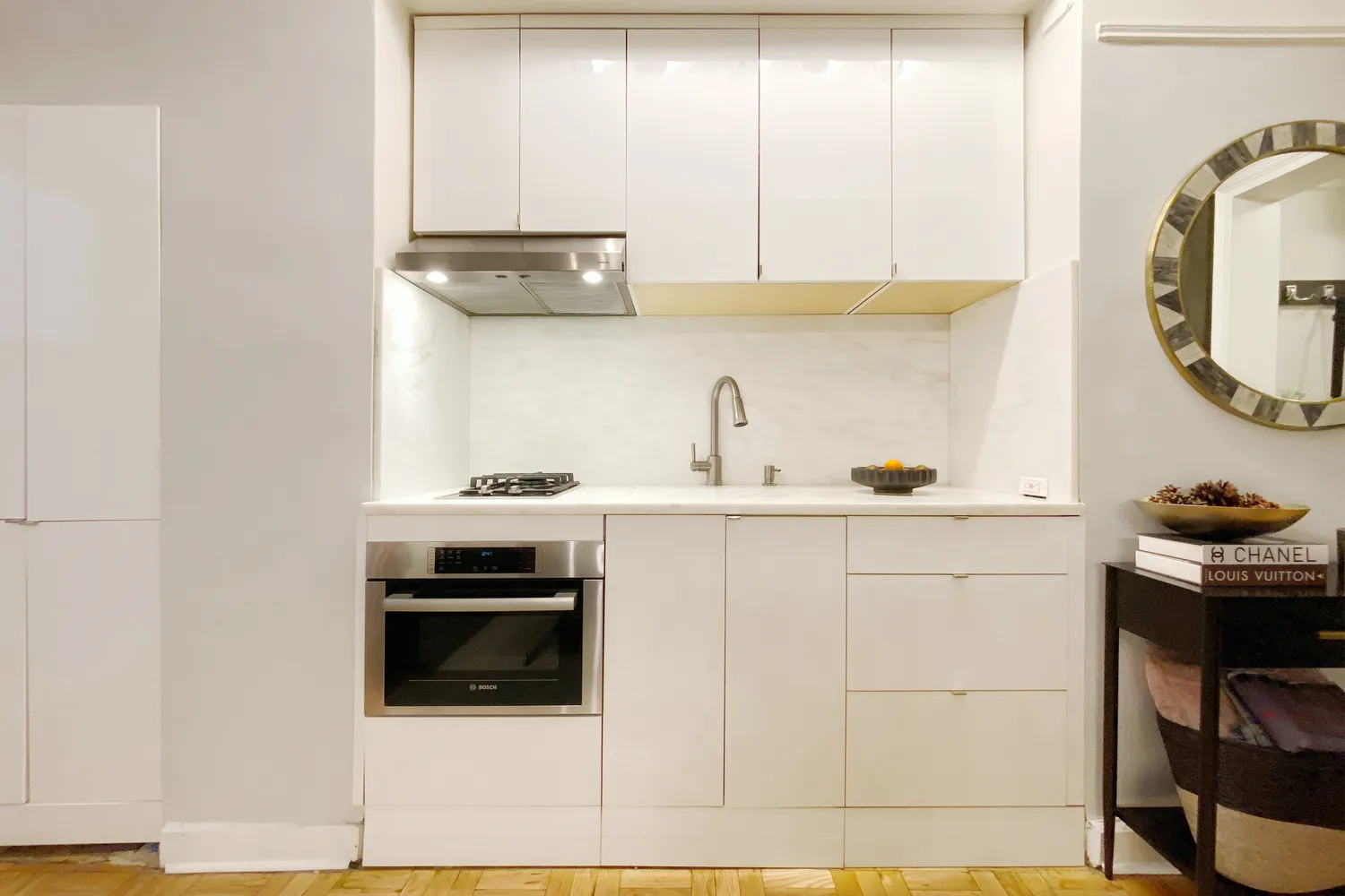 a kitchen with a sink and a stove with wooden floor