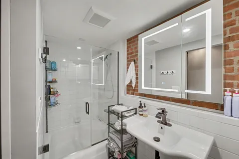 a bathroom with a sink shower and a mirror